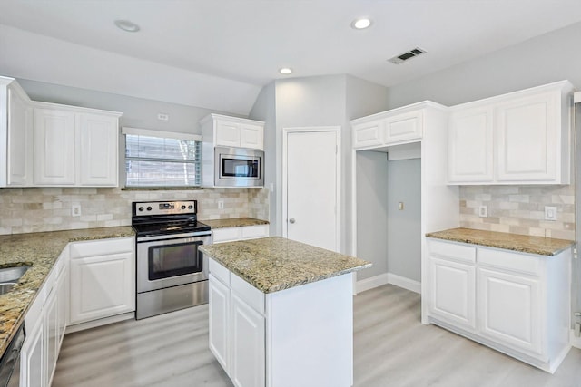 kitchen featuring light stone counters, appliances with stainless steel finishes, a kitchen island, and white cabinets