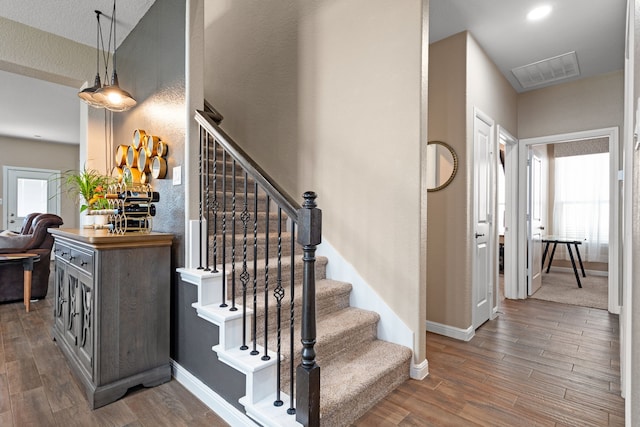 stairs with hardwood / wood-style floors and a healthy amount of sunlight