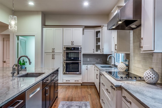 kitchen featuring stainless steel appliances, sink, white cabinets, and range hood