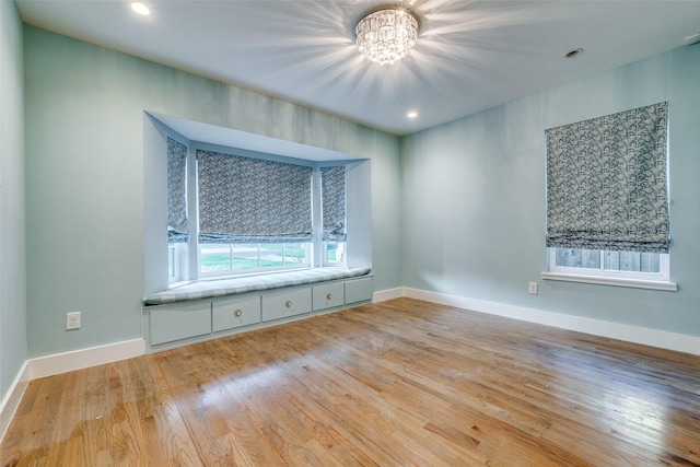 empty room with an inviting chandelier and light hardwood / wood-style floors