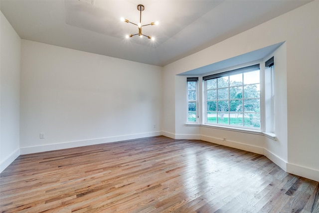 unfurnished room with a notable chandelier and light hardwood / wood-style flooring