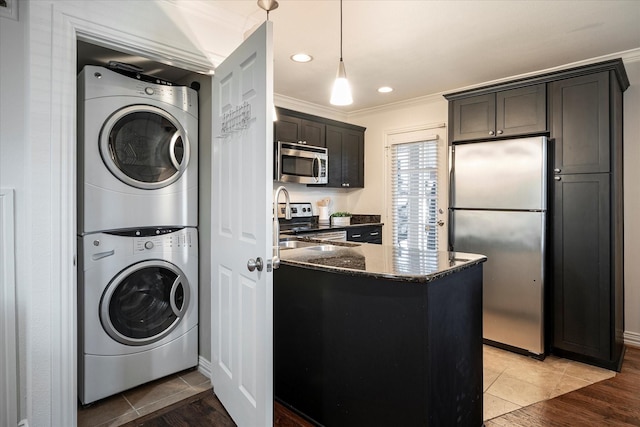 washroom featuring ornamental molding, stacked washer and clothes dryer, and light hardwood / wood-style floors