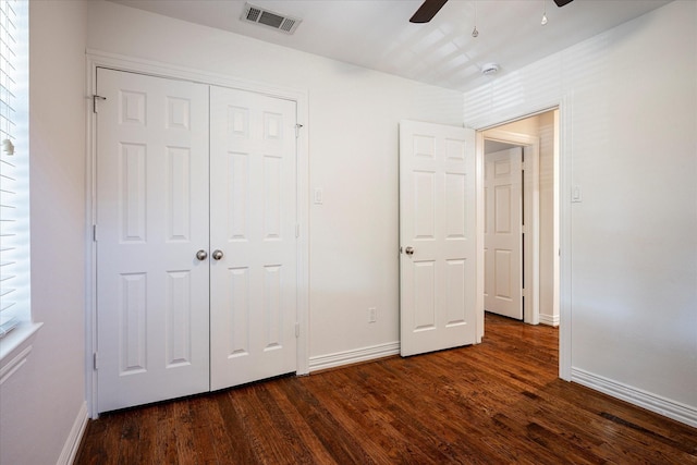 unfurnished bedroom with dark hardwood / wood-style flooring, a closet, and ceiling fan