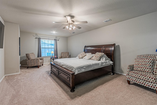 bedroom featuring ceiling fan, light colored carpet, and a textured ceiling