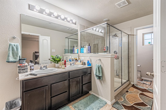 bathroom with vanity, hardwood / wood-style floors, an enclosed shower, and a textured ceiling