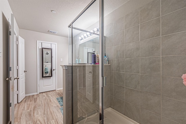 bathroom with an enclosed shower, hardwood / wood-style floors, and a textured ceiling