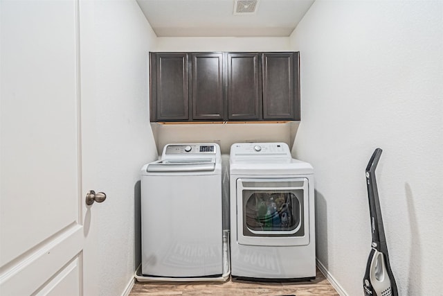 washroom featuring cabinets, light hardwood / wood-style floors, and washer and dryer