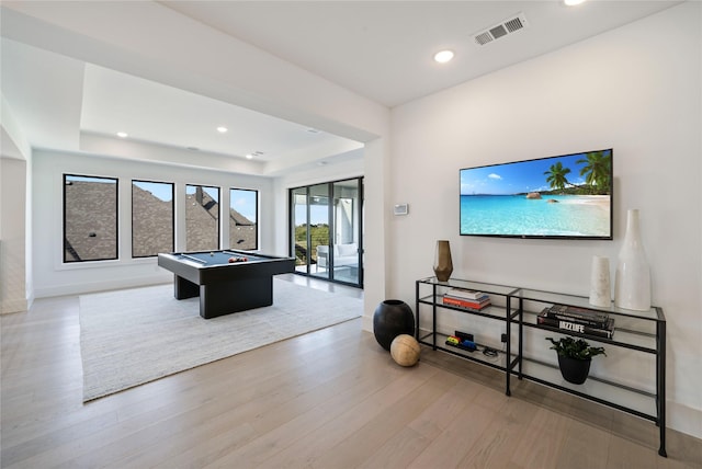 recreation room featuring a tray ceiling, light hardwood / wood-style flooring, and pool table