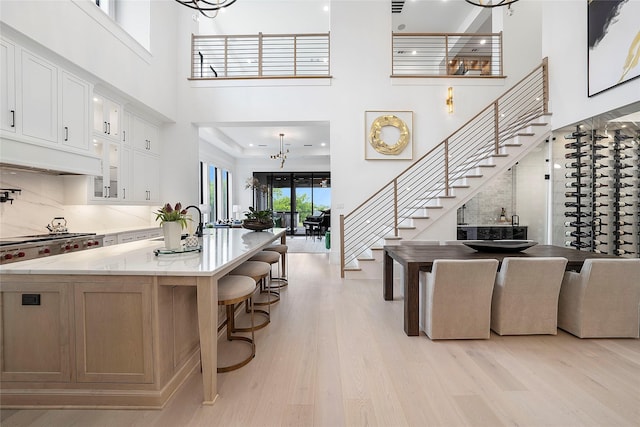 kitchen featuring white cabinetry, a large island, light wood-type flooring, and light stone counters