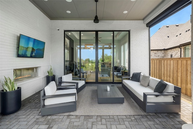 view of patio / terrace with ceiling fan and an outdoor living space with a fireplace