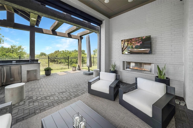 view of patio / terrace with an outdoor living space with a fireplace and exterior kitchen