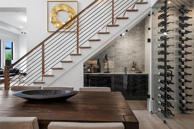 wine area featuring light wood-type flooring and a high ceiling