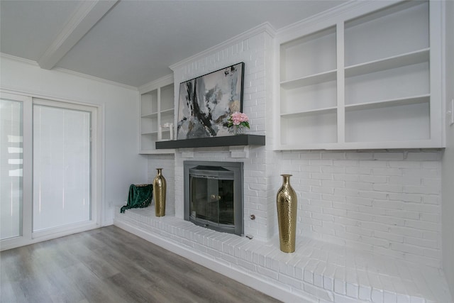 unfurnished living room with hardwood / wood-style flooring, ornamental molding, a brick fireplace, and built in shelves