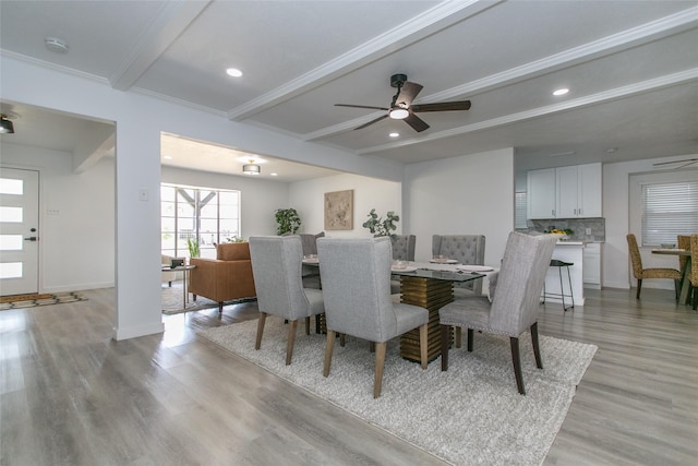 dining space with ceiling fan, ornamental molding, beamed ceiling, and light wood-type flooring