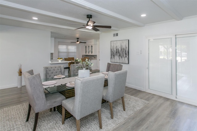 dining room with crown molding, beamed ceiling, and light wood-type flooring