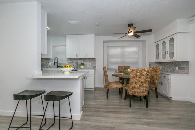 kitchen featuring white cabinetry, decorative backsplash, light wood-type flooring, and kitchen peninsula