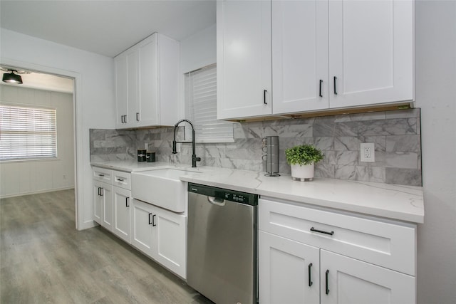 kitchen with tasteful backsplash, white cabinetry, stainless steel dishwasher, and light hardwood / wood-style flooring