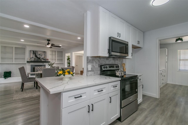 kitchen with white cabinetry, appliances with stainless steel finishes, kitchen peninsula, and light stone countertops