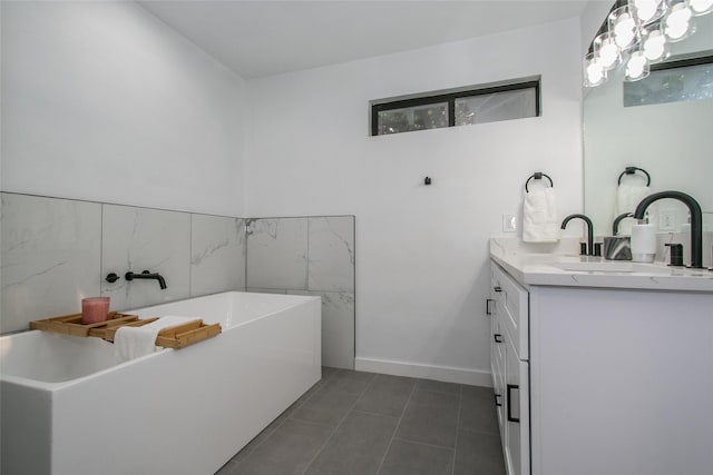 bathroom with a tub to relax in, vanity, and tile patterned floors