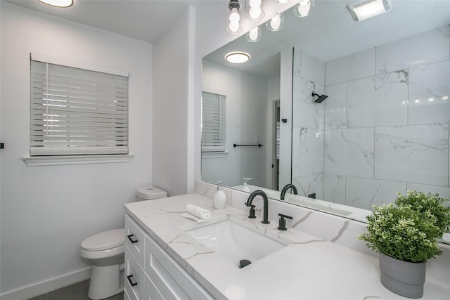 bathroom with vanity, tiled shower, and toilet