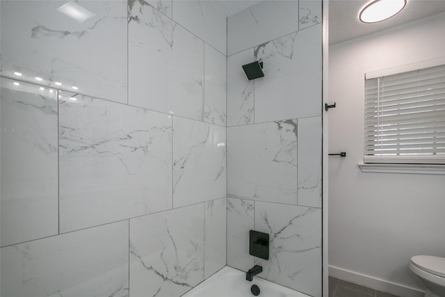 bathroom with toilet and tiled shower / bath