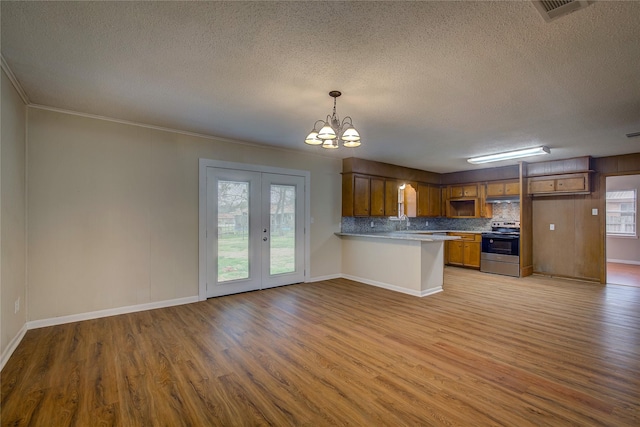 kitchen featuring hanging light fixtures, light hardwood / wood-style floors, french doors, stainless steel range with electric cooktop, and kitchen peninsula