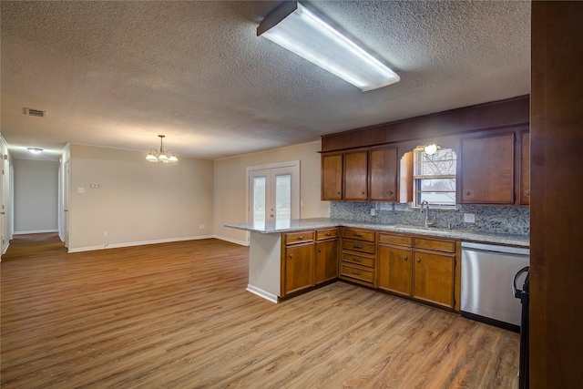 kitchen with sink, hanging light fixtures, stainless steel dishwasher, kitchen peninsula, and light wood-type flooring