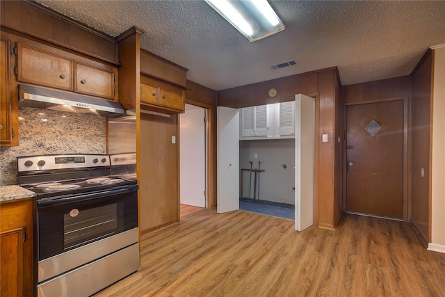 kitchen featuring electric stove, backsplash, light stone counters, a textured ceiling, and light hardwood / wood-style flooring