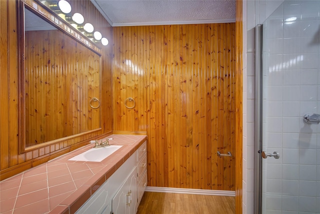 bathroom with hardwood / wood-style flooring, vanity, ornamental molding, a textured ceiling, and walk in shower