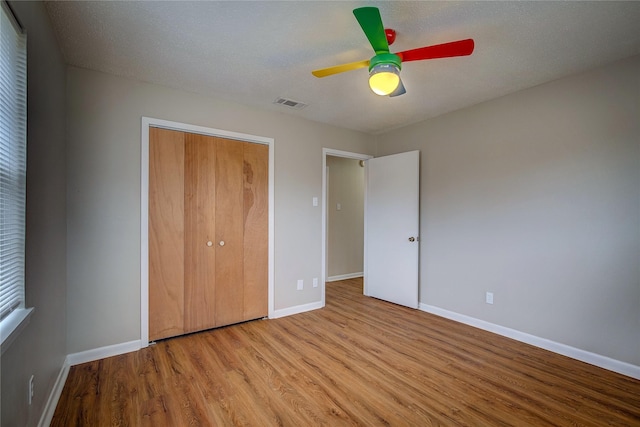 unfurnished bedroom featuring a textured ceiling, light hardwood / wood-style floors, a closet, and ceiling fan