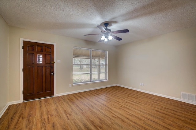 entrance foyer featuring visible vents, a textured ceiling, wood finished floors, baseboards, and ceiling fan