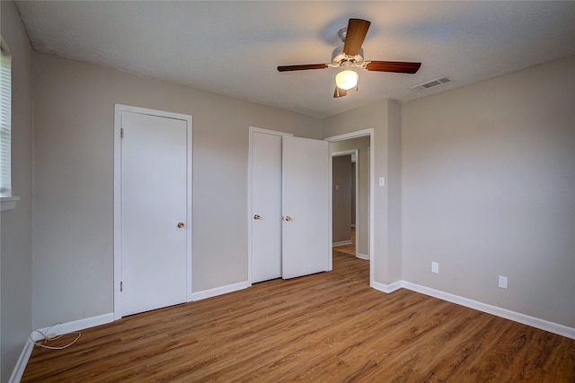 unfurnished bedroom with multiple closets, ceiling fan, and light hardwood / wood-style flooring