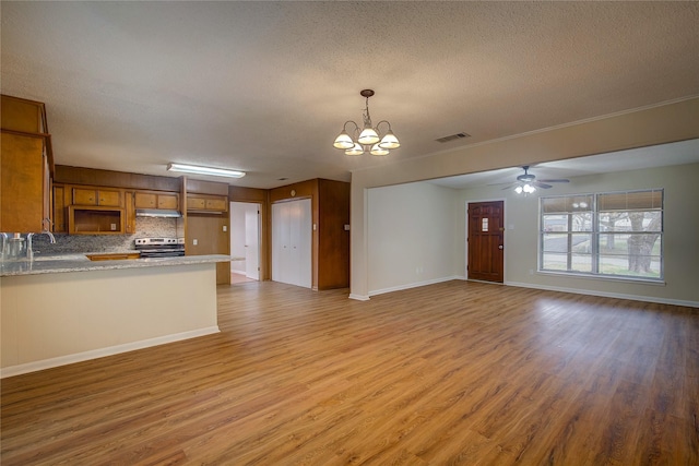 unfurnished living room with hardwood / wood-style flooring, ceiling fan with notable chandelier, and a textured ceiling