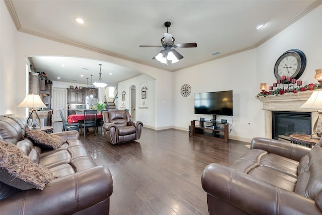 living room with crown molding, dark wood-type flooring, and ceiling fan