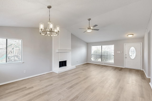 unfurnished living room with light hardwood / wood-style flooring, ceiling fan with notable chandelier, a fireplace, and lofted ceiling