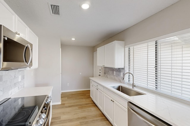 kitchen with stainless steel appliances, sink, light hardwood / wood-style flooring, and white cabinets