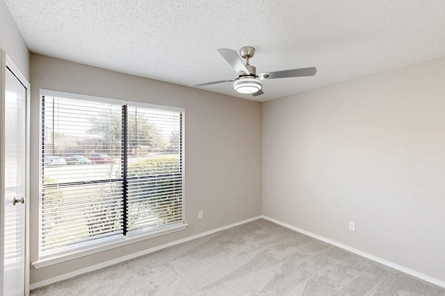 carpeted spare room with ceiling fan, plenty of natural light, and a textured ceiling