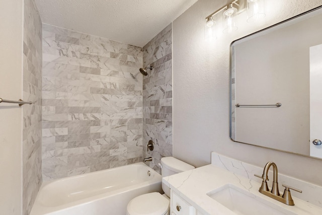 full bathroom featuring vanity, tiled shower / bath, toilet, and a textured ceiling