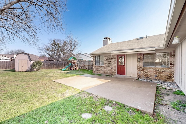 view of yard featuring a shed, a playground, and a patio