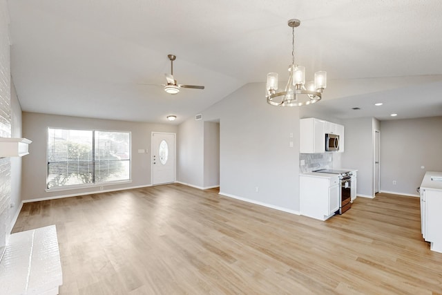 interior space featuring stainless steel appliances, lofted ceiling, white cabinets, and light hardwood / wood-style floors