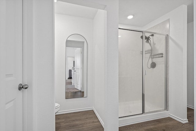 bathroom with wood-type flooring, toilet, and a shower with shower door