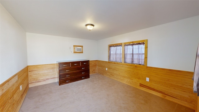 unfurnished bedroom with wooden walls and light carpet