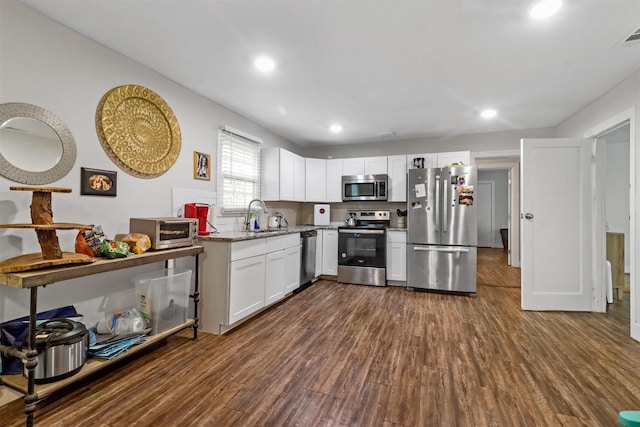 kitchen featuring sink, stainless steel appliances, light stone countertops, white cabinets, and dark hardwood / wood-style flooring