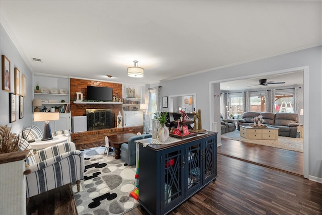 living room with crown molding, a fireplace, dark hardwood / wood-style flooring, and built in shelves