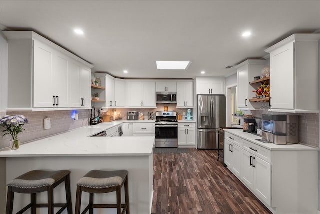 kitchen with white cabinetry, appliances with stainless steel finishes, kitchen peninsula, and a breakfast bar area