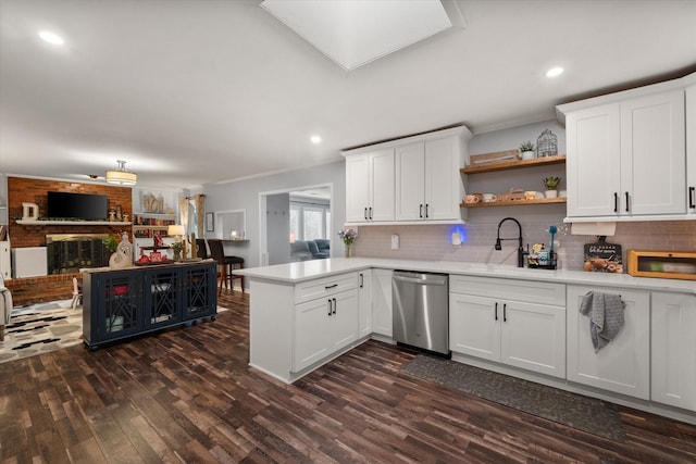 kitchen with stainless steel dishwasher, a fireplace, kitchen peninsula, and white cabinets