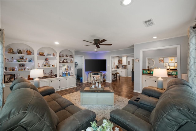 living room featuring dark hardwood / wood-style flooring, crown molding, built in features, and ceiling fan