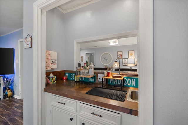 bar featuring crown molding, white cabinetry, and dark hardwood / wood-style floors