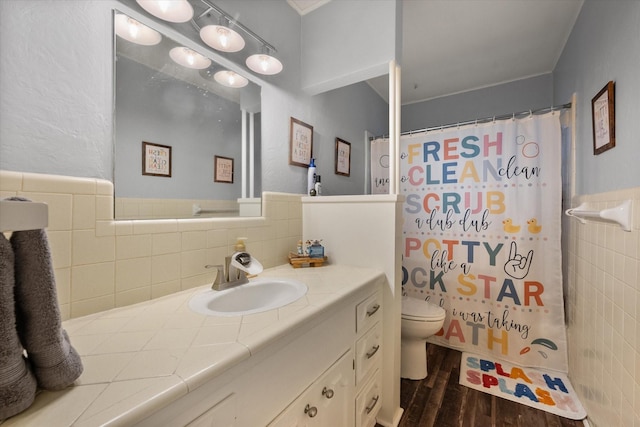 bathroom with toilet, wood-type flooring, tile walls, vanity, and curtained shower