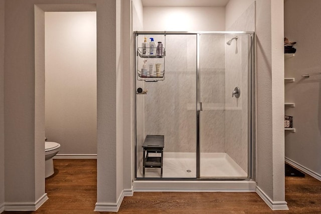 bathroom with wood-type flooring, walk in shower, and toilet